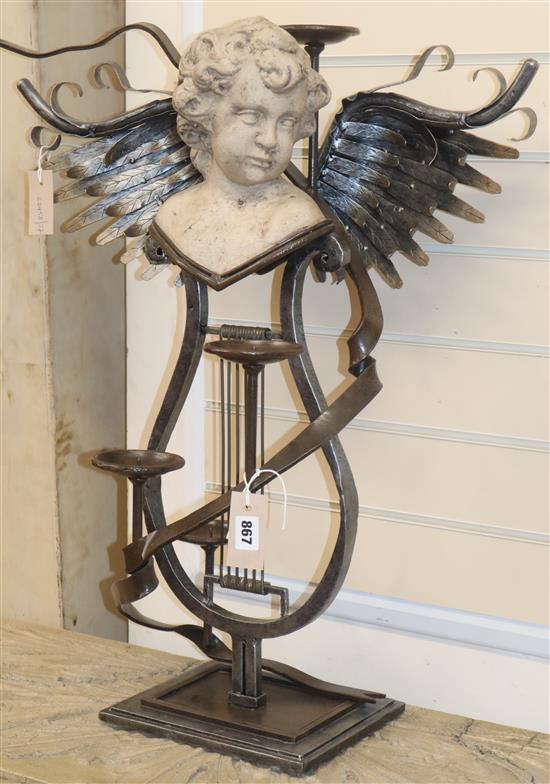 A wrought iron three branch candelabra with lyre shaped base, surmounted with reconstituted stone head of a putti H.72cm